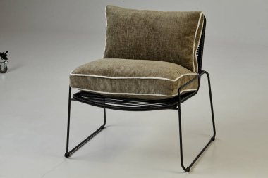 Zeytin yeşili yastıkları ve siyah metal çerçeveli rahat modern koltuk, beyaz arka planda izole edilmiş, iç tasarım projeleri için mükemmel.