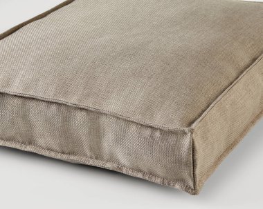 Büyük, bej kare bir yastığın yakın plan dikimi, rahat ve şık bir oturma seçeneği sunuyor.