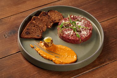 Gurme sığır etli tart zarif bir şekilde çeşitli eşliklerle sunuluyor, görsel olarak çekici bir mutfak deneyimi yaratıyor.