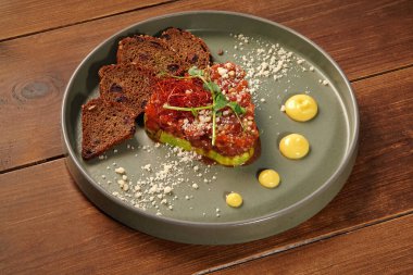 Avokado, çavdar ekmeği ve bir tabak sosla servis edilen gurme somon tartını.