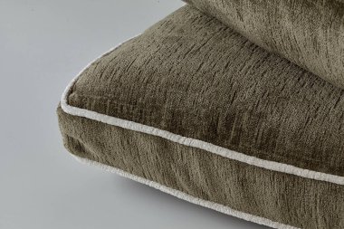 Zıt beyaz boruları olan zeytin yeşili yastıklar lüks ve rahat bir his yaratır.