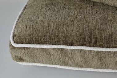 Yumuşak dokuyu ve zarif tasarımı gösteren, beyaz boru döşeme detaylarıyla kahverengi yastığın yakın plan görüntüsü