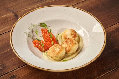 Patates püresi ve sebze soslu tavuk pirzolası bir restorandaki ahşap bir masada beyaz bir tabakta servis edilir.