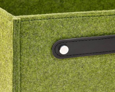 Kaliteli malzeme ve işçiliğin ön plana çıkarıldığı, metal perçin ile korunan siyah deri saplı şık yeşil keçeli bir kutuya yakın plan.