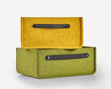 Deri saplı iki renkli keçeli kutu beyaz arka planda duruyor ve şık ve pratik bir depolama çözümü sunuyor.