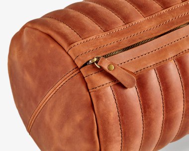 Kahverengi deri çanta ayrıntılı dikişler ve pirinç fermuar, kaliteli işçilik ve zamansız tasarım.