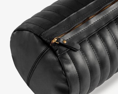 Pirinç fermuarlı şık silindirik siyah deri bir çantanın yakın plan çekimi, işçilik ve minimalist tasarım.