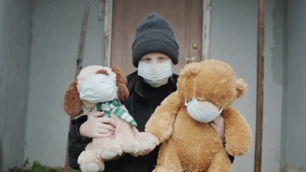 マスクをした子供は マスクを身に着けているおもちゃを保持します 君の家の玄関先だ うつ病と隔離 — ストック動画