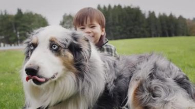 Kaygısız, neşeli bir çocuk büyük bir çoban köpeğinin arkasından dışarı bakıyor. Sevdiğim bir arkadaşımla yürüyorum..