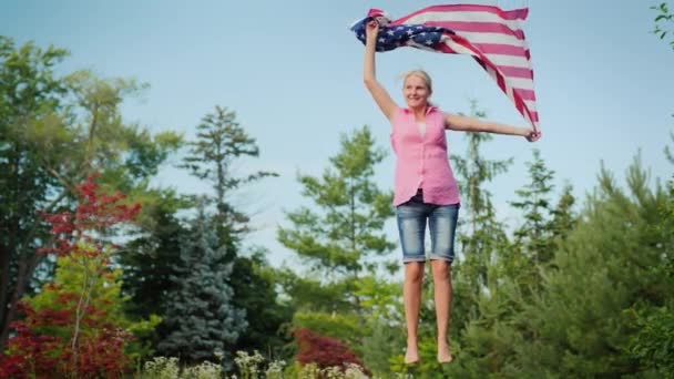 Attraktiv Kvinna Med Den Amerikanska Flaggan Hoppar Studsmatta Trädgården Självständighetsdagen — Stockvideo