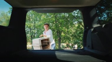 Bir kadın, köpekli iki kafesi bir arabanın bagajına koyar. Hayvanların araçlarla taşınması.