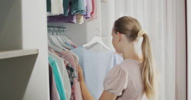 A teenager chooses a dress in the dressing room