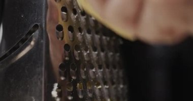 Bir adam rendeleyiciye sert peynir sürer, yakın plan. Lezzetli bir yemek için yemek malzemeleri..