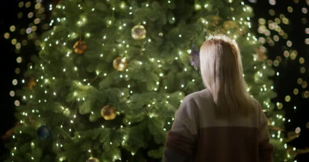 Μια Γυναίκα Στολίζει Ένα Χριστουγεννιάτικο Δέντρο Χριστουγεννιάτικο Δέντρο Λάμπει Φώτα — Αρχείο Βίντεο