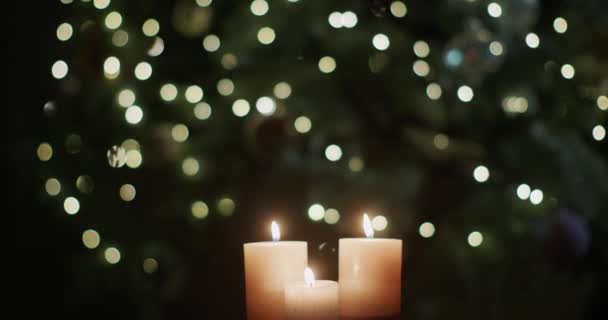 Três Velas Ardem Contra Pano Fundo Luzes Embaçadas Árvore Natal — Vídeo de Stock