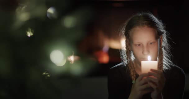 Nastolatka Trzyma Płonącą Świecę Rękach Siedzi Przy Choince Tle Płonie — Wideo stockowe