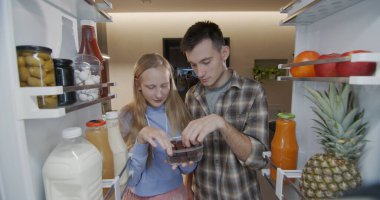 Erkek ve kız kardeş buzdolabını açın ve şeker yiyin. Abur cubur..