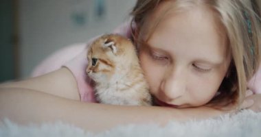 Portrait of a child with a kitten looking at the camera.