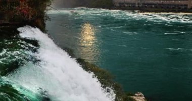 Niagara Şelalesi 'nde akşam. Nehir batan güneşi yansıtır, ön planda güçlü bir su akıntısı..