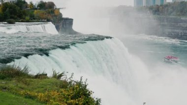 Ünlü Niagara Şelalesi, New York ve Amerika 'nın bir simgesidir. Nehrin kıyısında turistlerle dolu bir tekne yüzüyor. 4k video