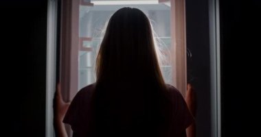 A young woman opens the doors of an empty refrigerator