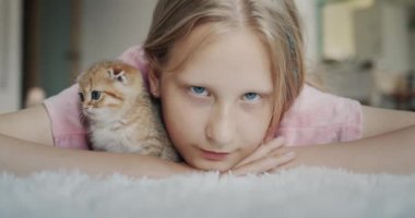 Portrait of a child with a kitten looking at the camera.