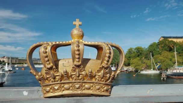 背後に港がある川にかかる橋の上にあるスウェーデン王室の王冠 街の観光スポットの一つ スタディカムが撃たれた — ストック動画