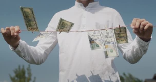 一个男人拿着一条挂钞票的晾衣绳 风使他们动摇 非法收入概念 — 图库视频影像