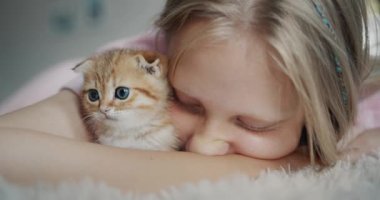 Çocuk yanağını kızıl kediye bastırır, evcil hayvanın mutlu sahibine..