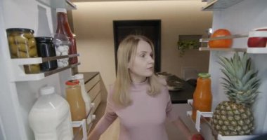 Akşamın ilerleyen saatlerinde, bir kadın buzdolabına bakar ve şeker yer. Gece atıştırma ve yeme bozuklukları.