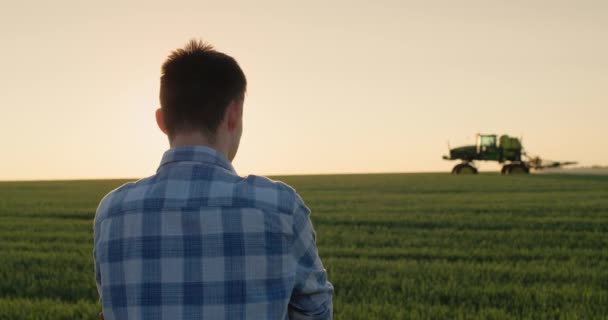 Genç Bir Erkek Çiftçi Traktörün Çalıştığı Buğday Tarlasına Bakar — Stok video