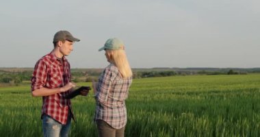 İki çiftçi buğday tarlaları olan pitoresk bir arazinin zeminine karşı konuşuyor.