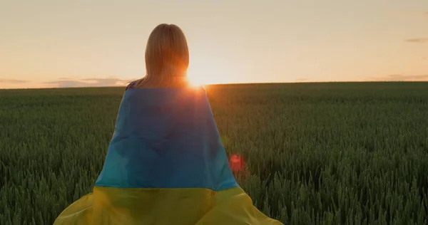 Kobieta Flagą Ukrainy Ramionach Patrzy Wschód Słońca Nad Polem Pszenicy — Zdjęcie stockowe