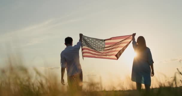 日落时分 一男一女在麦田上升起美国国旗 美国独立日的概念 — 图库视频影像