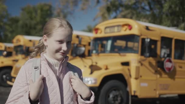 Портрет Школьницы Перед Рядом Школьных Автобусов — стоковое видео