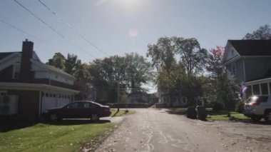 Açık bir sonbahar gününde tipik bir Amerikan kasabası caddesi boyunca sür. Arka pencere görünümü.