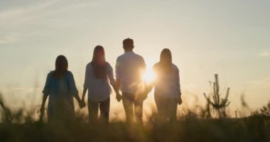 Bir grup arkadaşın silueti. Batan güneşin arka planına karşı ellerini kaldır. Takım çalışması ve başarı kavramı.