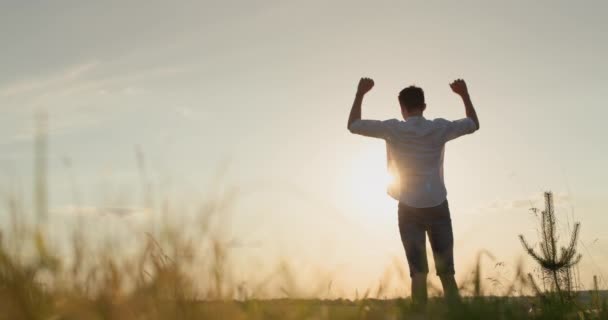 Nuori Energinen Mies Nostaa Kätensä Ylös Seisoo Auringonlaskun Aikaan Viehättävässä — kuvapankkivideo