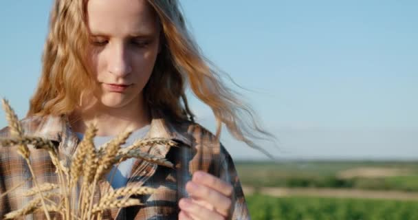 一个手里拿着麦穗的少女的画像 以风景如画的乡村为背景 — 图库视频影像