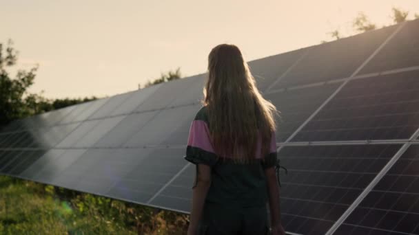 一个少女沿着一家小发电厂的太阳能电池板走着 — 图库视频影像