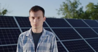 Portrait of a young man against the background of solar power plant panels.