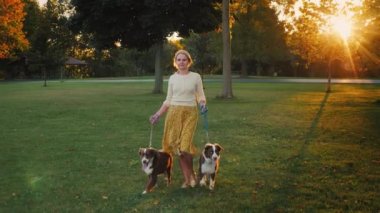 Active middle aged woman walking in the park with her two dogs.
