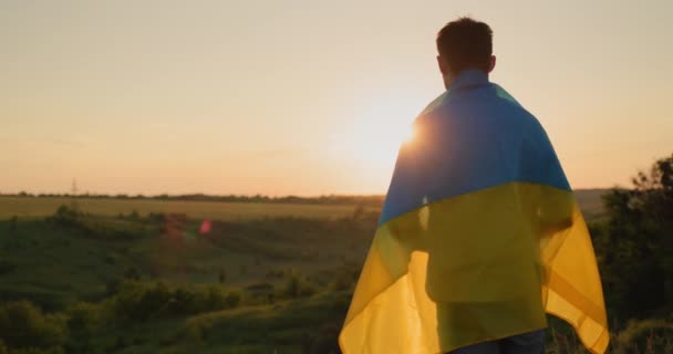 Молодой Человек Флагом Украины Плечах Смотрит Закат Над Живописной Долиной — стоковое видео
