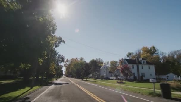 秋の晴れた日にアメリカの町の典型的な通りに沿ってドライブします 後部ウィンドウ表示 — ストック動画