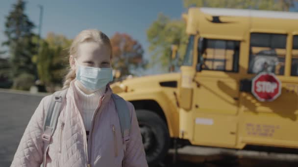 Een Schooljongen Met Een Beschermend Masker Staat Voor Een Schoolbus — Stockvideo