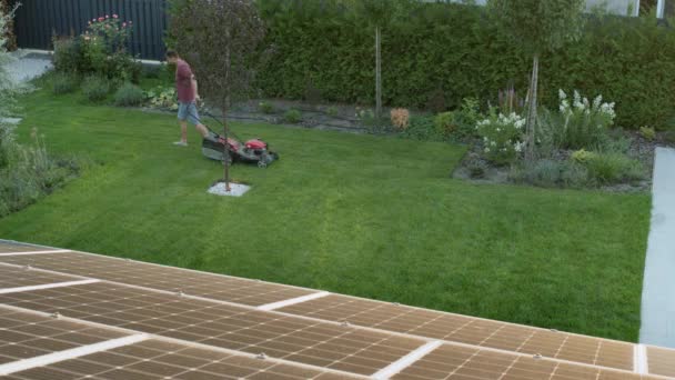 男人在房子的后院里修剪草坪 俯瞰四周 — 图库视频影像