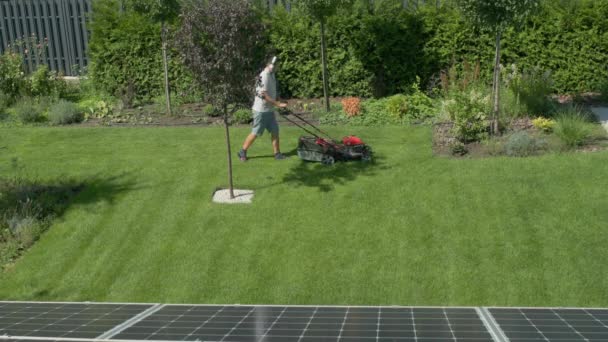 家の裏庭で芝生を刈る男 トップビュー — ストック動画