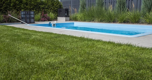 stock image Swimming pool in the backyard of the house with an open hatch to the technical room. Radom vacuum cleaner for cleaning the bottom.