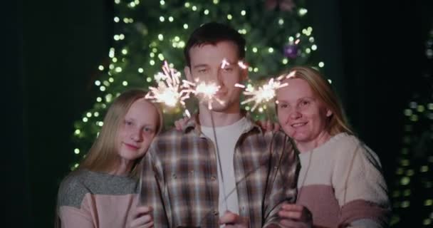 在圣诞树旁 一个快乐的家庭举着熊熊燃烧的火花庆祝新年 — 图库视频影像