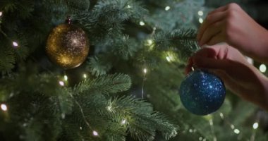 Çocukların elleri Noel ağacına mavi bir top asar..